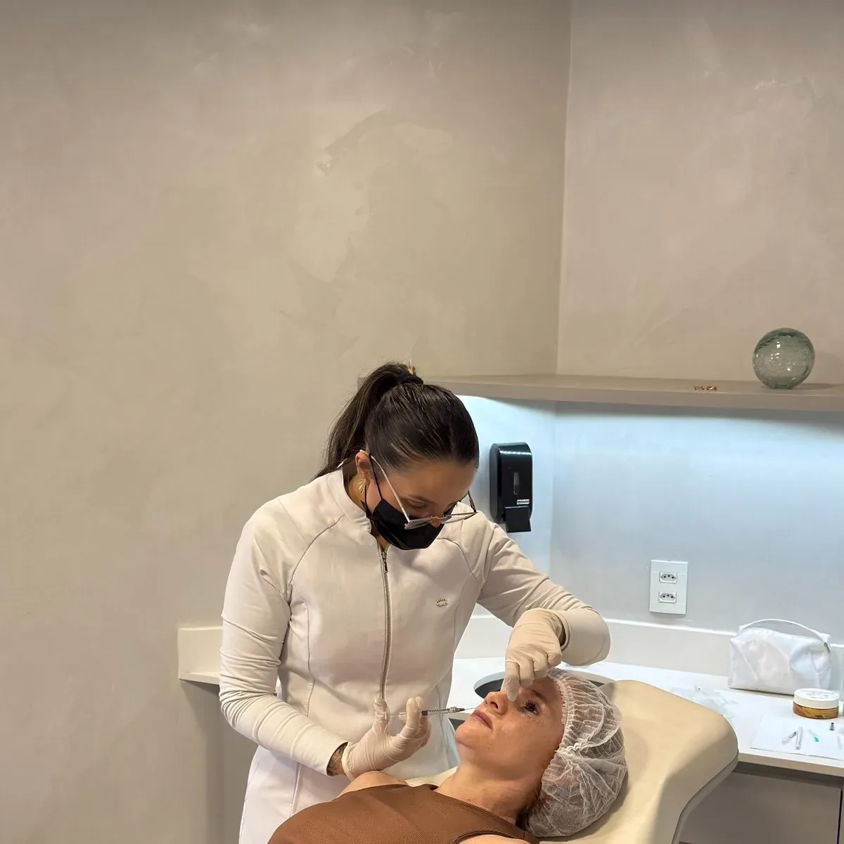 Dra. Clara Paiva realizando atendimento facial em consultório